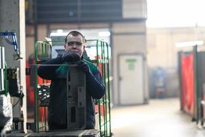 a uniformed worker working in a modern metal production and processing factory assembles parts of a new machine on his desk photo