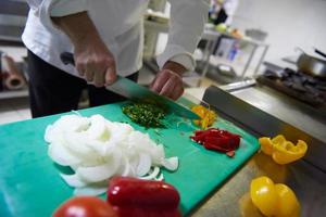 chef in hotel kitchen  slice  vegetables with knife photo
