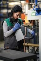 una mujer que trabaja en una fábrica de metal moderna ensambla piezas para una nueva máquina foto