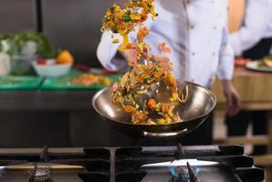 chef flipping vegetables in wok photo