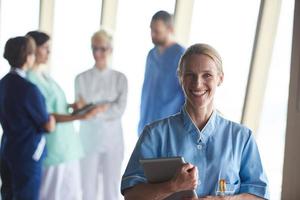 female doctor with tablet computer  standing in front of team photo