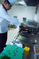 chef in hotel kitchen prepare food with fire photo