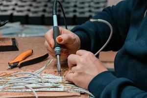 mujer trabajadora industrial soldando cables de equipos de fabricación en una fábrica foto