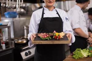 female Chef holding beef steak plate photo