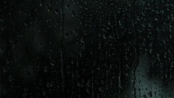 gotas de lluvia en el cristal. pequeña gota de lluvia descansa sobre el vidrio mientras llueve. video