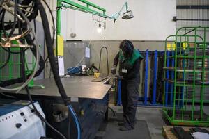 una mujer que trabaja en la industria moderna de producción y procesamiento de metales soldando el producto y preparándolo para una máquina cnc foto