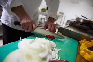 chef in hotel kitchen  slice  vegetables with knife photo