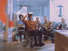 Disabled businessman in a wheelchair at work in modern open space coworking office with team using virtual reality googles drone assistance simulation photo