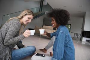 young multiethnic women sit on the floor and drinking coffee photo
