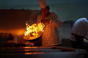 chef in hotel kitchen prepare food with fire photo