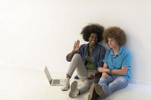 multiethnic couple sitting on the floor with a laptop and tablet photo