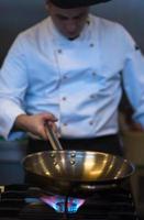 chef preparing food, frying in wok pan photo