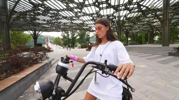 mujer joven monta scooter eléctrico en un día soleado video