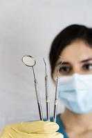 young female dentist holding dental instruments in her hand photo