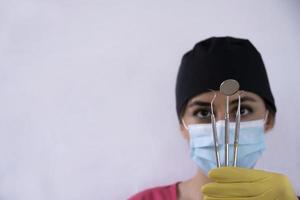 joven dentista sosteniendo instrumentos dentales en la mano foto