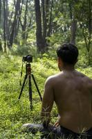 chico milenario meditando con un entrenador en línea a través de una conexión de tablet ipad, en el bosque, transmitiendo en línea tu clase e instrucciones, méxico foto