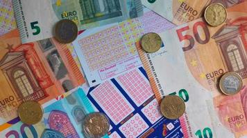 Rotierender Stapel französischer Lotto- und Glücksspiele mit Euro-Banknoten und -Münzen darauf video