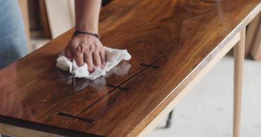 mestre carpinteiro aplicando óleo de móveis na mesa de nogueira sólida. parte 1 video