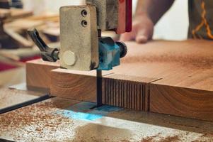 A man cuts wood on a circular saw in a joinery, band saw, holding a plank photo