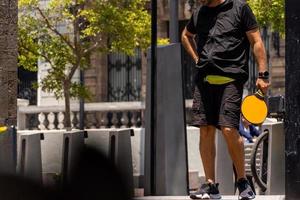 young man, gramde man playing paddle tennis in the street photo