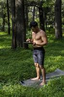 un yogui activo y guapo camina en un parque paseando por el bosque antes o después de un entrenamiento. joven atlético hispano clase de yoga con una alfombra de fitness foto