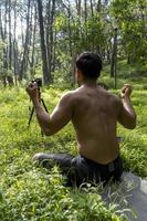 Millennial guy meditating with trainer online via tablet ipad connection, in the forest, broadcasting online your class and instructions, mexico photo