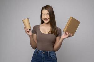 Young asian woman holding paper cup and paper box over white background, Save earth concept photo