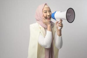 Young beautiful woman holding megaphone over white background studio. photo