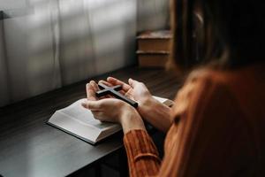 Woman sitting and studying the scriptures.The  wooden cross in the hands. Christian education concepts The Holy Scriptures open and pray to God photo