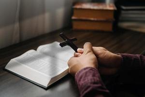 Woman sitting and studying the scriptures.The  wooden cross in the hands. Christian education concepts The Holy Scriptures open and pray to God. photo