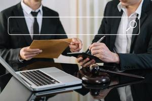 negocios y abogados discutiendo documentos contractuales con barra de búsqueda en blanco. concepto de justicia y derecho. juez masculino en una sala de audiencias con el mazo, trabajando con una tableta digital. foto