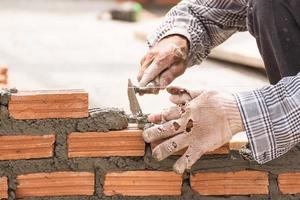 Bricklayer working in construction site of a brick wall photo