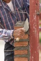 Bricklayer working in construction site of  brick wall photo