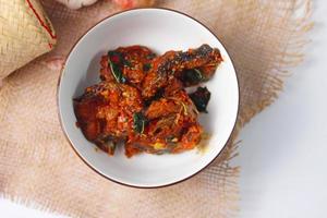 Spicy Stir Fried Catfish served in a Thai style patterned bowl on a white table. photo