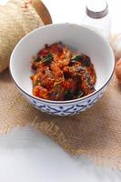 Spicy Stir Fried Catfish served in a Thai style patterned bowl on a white table. photo