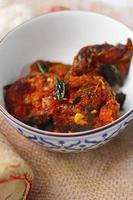 Spicy Stir Fried Catfish served in a Thai style patterned bowl on a white table. photo