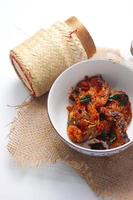 Spicy Stir Fried Catfish served in a Thai style patterned bowl on a white table. photo