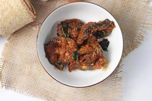 Spicy Stir Fried Catfish served in a Thai style patterned bowl on a white table. photo