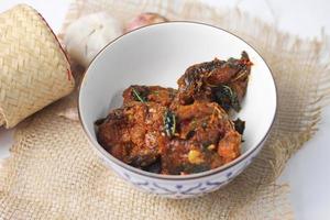 Spicy Stir Fried Catfish served in a Thai style patterned bowl on a white table. photo