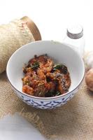 Spicy Stir Fried Catfish served in a Thai style patterned bowl on a white table. photo