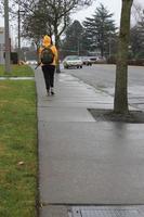 Seattle, America - ,March 09 - 2022  A woman in a yellow raincoat is walking on a damp sidewalk. photo