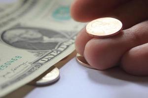 Man's hand picking up penny or cent coin from a pile of banknotes and coins. photo