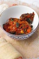 Spicy Stir Fried Catfish served in a Thai style patterned bowl on a white table. photo