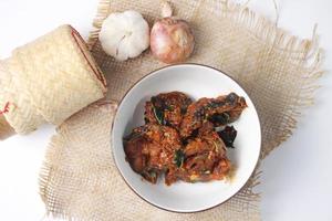 Spicy Stir Fried Catfish served in a Thai style patterned bowl on a white table. photo