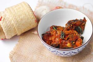 Spicy Stir Fried Catfish served in a Thai style patterned bowl on a white table. photo
