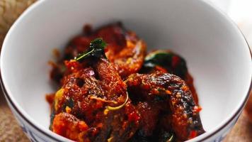 Spicy Stir Fried Catfish served in a Thai style patterned bowl on a white table. photo