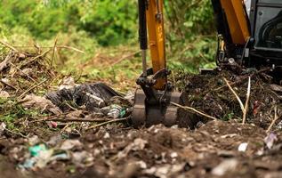 Backhoe digging soil at construction site. Bucket of backhoe digging soil. Clearing and grubbing. Digger working at road construction site. Earth moving machine. Excavation vehicle. Land development. photo