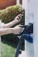 Hand plugging in a charger in an electric car socket.Electric car or ev is charging at station photo