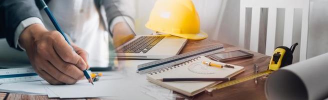 Two colleagues discussing data working and tablet, laptop with on on architectural project at construction site at desk in office photo