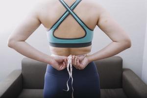 hermosa mujer gorda con cinta métrica usa su mano para exprimir el exceso de grasa que está aislado en un fondo blanco. ella quiere perder peso, el concepto de cirugía y descomponer grasa bajo el foto